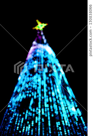 Christmas tree decorated with garlands and ornaments. Blurry festive lights glowing on green fir 130838066