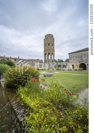 Charroux Abbey tower rising above colorful flowers in Nouvelle Aquitaine, France 130838509