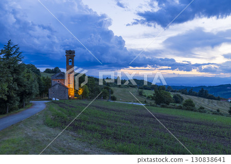 Illuminated Church Stands on Hilltop in Piedmont, Italy at Dusk 130838641