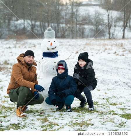 Family building a snowman together on a snowy day. Family building a snowman together on a snowy day. 130838892