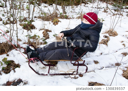 Child enjoying a snowy day, pulled along on a vintage sled through a winter wonderland. Child enjoying a snowy day, pulled along on a vintage sled through a winter wonderland. 130839337