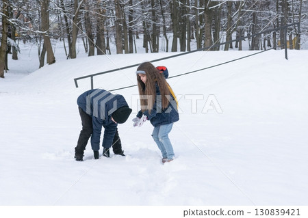 Children playfully build a snow fort together in a snowy park, enjoying winter's fun. 130839421