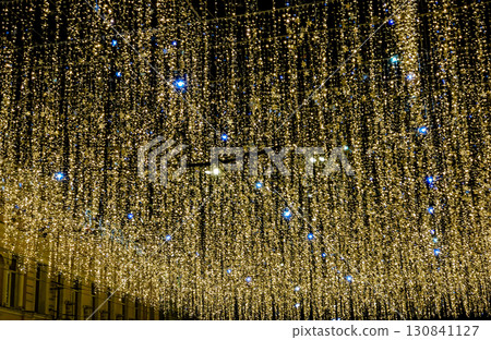 A mesmerizing night shot of a street or public square ceiling, covered by thousands of shimmering golden and blue fairy lights A mesmerizing night shot of a street or public square ceiling, covered by thousands of shimmering golden and blue fairy lights 130841127
