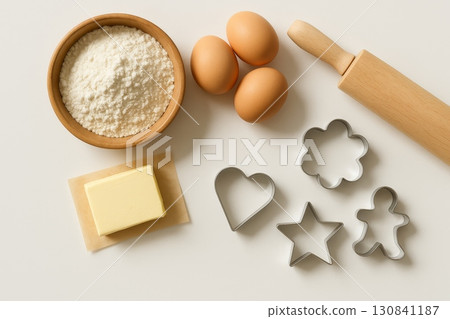 Baking ingredients and tools: flour, butter, eggs, rolling pin, and cookie cutters on light background. Baking ingredients and tools: flour, butter, eggs, rolling pin, and cookie cutters on light background. 130841187