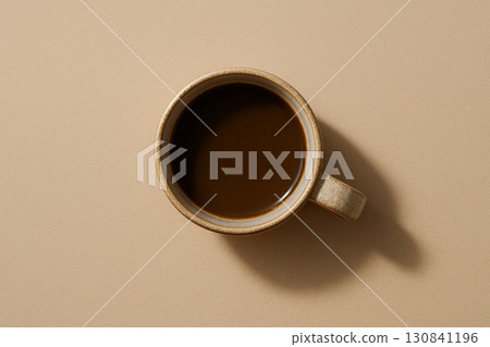 Top view of black coffee in ceramic cup on beige background with copy space. Minimalist coffee break concept. 130841196
