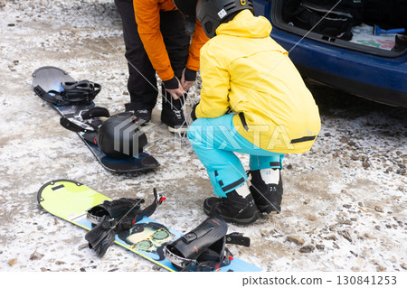 Excitement fills the air as snowboarders prepare their gear in a snowy mountain parking lot on a crisp winter morning 130841253