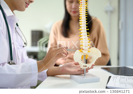 Physician pointing at spinal anatomy model while discussing diagnosis with patient Physician pointing at spinal anatomy model while discussing diagnosis with patient 130841271