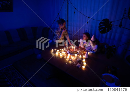 Celebration of joy with friends as candles illuminate the cozy room during a nighttime birthday party gathering filled with laughter and sweet treats 130841376