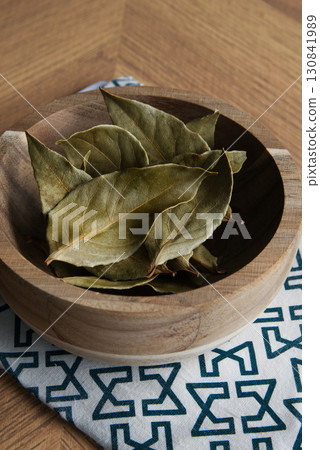Dried bay leaves in a wooden bowl on the table 130841989