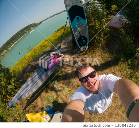 Couple Enjoying Lakeside Camping with Paddleboard 130842236