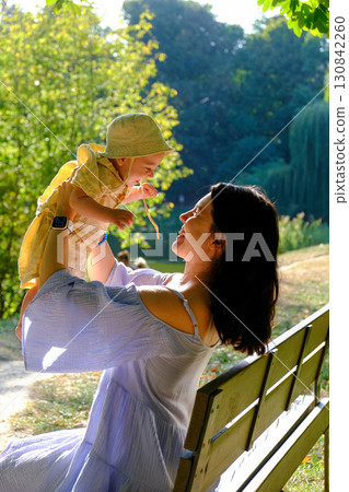 Mother Lifting Baby Outdoors in Sunny Park Mother Lifting Baby Outdoors in Sunny Park 130842260
