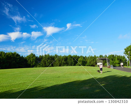 A woman jogging and people walking in a summer park 130842310