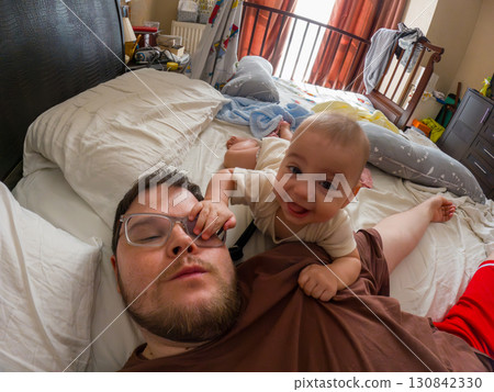 Father and Baby Playfully Bonding on Bed Father and Baby Playfully Bonding on Bed 130842330