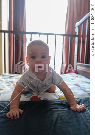 Baby Crawling in Crib with Colorful Bedspread 130842367
