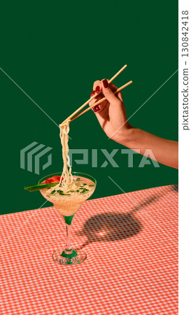 Hand with chopsticks lifting noodles from martini glass with tomato and onion garnish Hand with chopsticks lifting noodles from martini glass with tomato and onion garnish 130842418