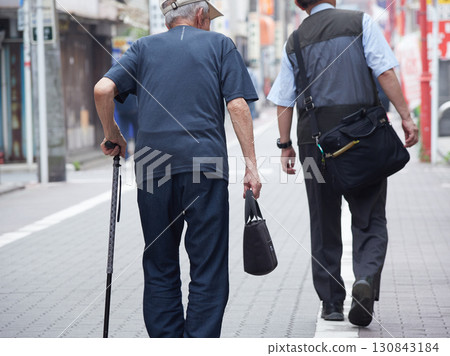 Senior man walking in a shopping street in a city in summer Senior man walking in a shopping street in a city in summer 130843184