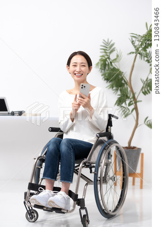 坐輪椅的女性透過家用智慧型手機工作 130843466