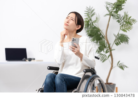 Woman in wheelchair, working from home, worries Woman in wheelchair, working from home, worries 130843478