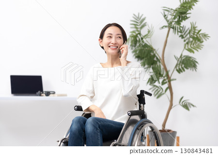 坐在輪椅上的女人在家工作，打電話 130843481