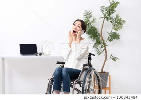 坐在輪椅上的女人在家工作,打電話,很驚訝 坐在輪椅上的女人在家工作,打電話,很驚訝 130843484