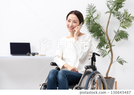 Woman in wheelchair, working from home, calling 130843487