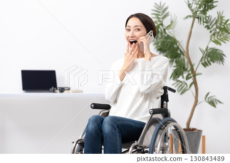 Woman in wheelchair, working from home, calling, surprised Woman in wheelchair, working from home, calling, surprised 130843489