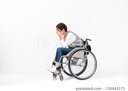 坐在輪椅上的憂心忡忡的女人，全身 130843571
