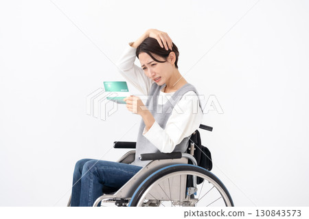 A woman in a wheelchair is depressed when she sees her bankbook 130843573