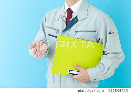 A middle-aged male businessman in work clothes holding a binder 130843755