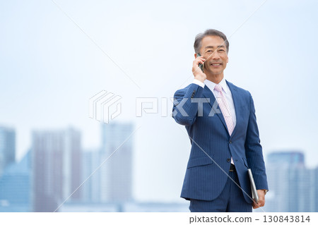 Businessman, buildings, smartphone 130843814