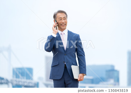 Businessman, buildings, smartphone 130843819
