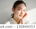 A Japanese woman in front of a white wall with natural light reflecting beautifully on her bare skin 130844353