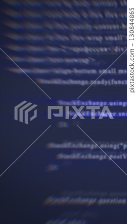 Abstract blurred digital code on a dark screen, representing programming, cybersecurity, and technology 130844865