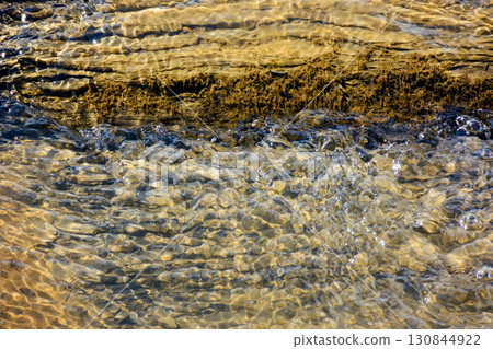 nature texture with stones in the water steam. closeup background of a river shore in autumn 130844922