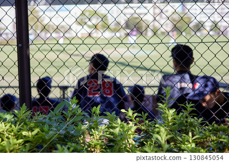 The backs of cheering baseball players seen through the fence The backs of cheering baseball players seen through the fence 130845054