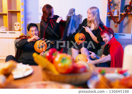 Dinner and group of people celebrating together at Halloween party. 130845198