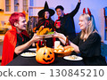 Dinner and group of people celebrating together at Halloween party. 130845210