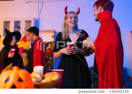 Dinner and group of people celebrating together at Halloween party. 130845216