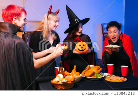 Dinner and group of people celebrating together at Halloween party. 130845218