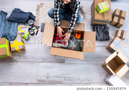 Girl Packing Cardboard Boxes With Clothes For Moving Girl Packing Cardboard Boxes With Clothes For Moving 130845974