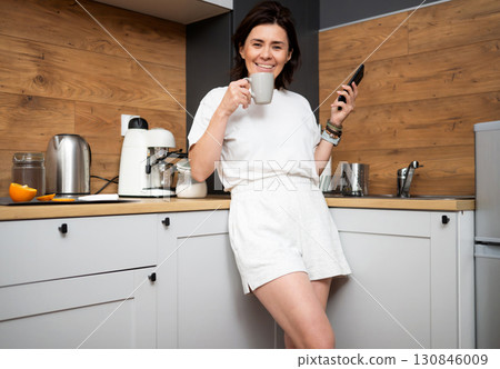 Happy Girl Drinking Fresh Coffee In A Cup In The Kitchen In The Morning 130846009