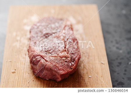 Raw ribeye steak spiced and ready to cook on oak board Raw ribeye steak spiced and ready to cook on oak board 130846034