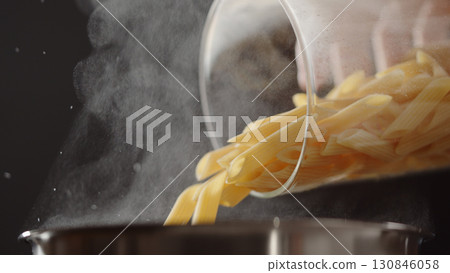 dry penne rigate poured in saucepan with boling water 130846058
