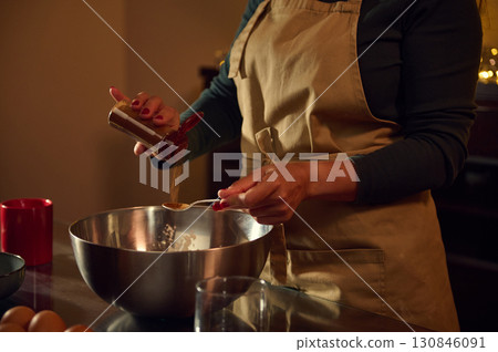 Woman Preparing Recipe in Kitchen with Warm Holiday Ambiance 130846091