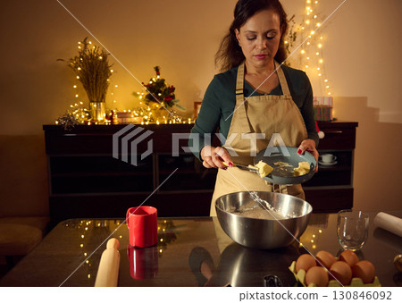 Woman Preparing Holiday Cookies in Festive Kitchen with Christmas Lights Woman Preparing Holiday Cookies in Festive Kitchen with Christmas Lights 130846092