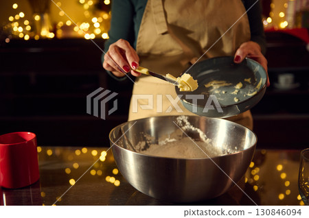 Woman Preparing Holiday Cookies in a Festive Kitchen with Christmas Lights 130846094