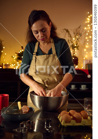 Woman Preparing Christmas Cookies in Festive Kitchen with Warm Lighting 130846099