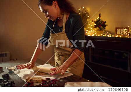 Woman Preparing Christmas Cookies Surrounded by Festive Lights in Cozy Kitchen 130846106