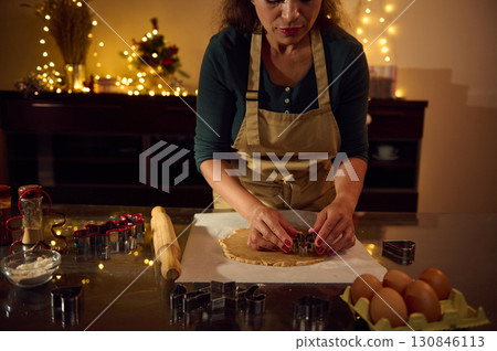 Woman Preparing Holiday Cookies in Festive Kitchen with Christmas Decorations Woman Preparing Holiday Cookies in Festive Kitchen with Christmas Decorations 130846113