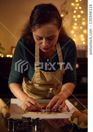 Woman Baking Holiday Cookies with Festive Christmas Decorations and Warm Lights Woman Baking Holiday Cookies with Festive Christmas Decorations and Warm Lights 130846116